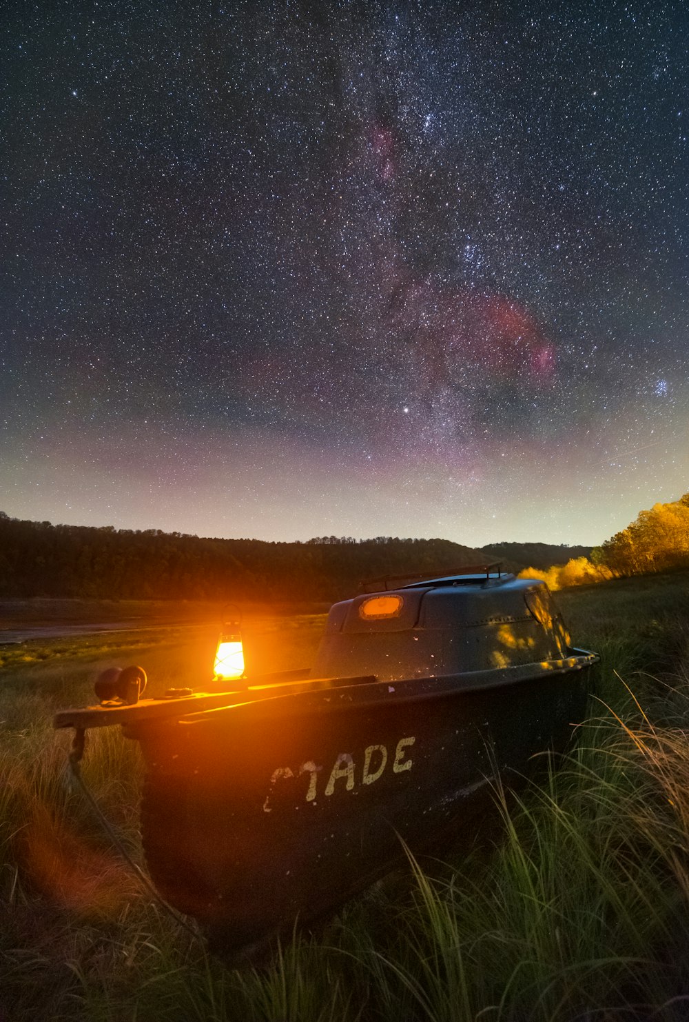 a boat sitting on top of a lush green field under a night sky
