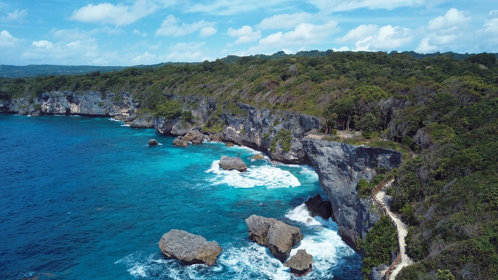 an aerial view of the ocean with rocks in the foreground