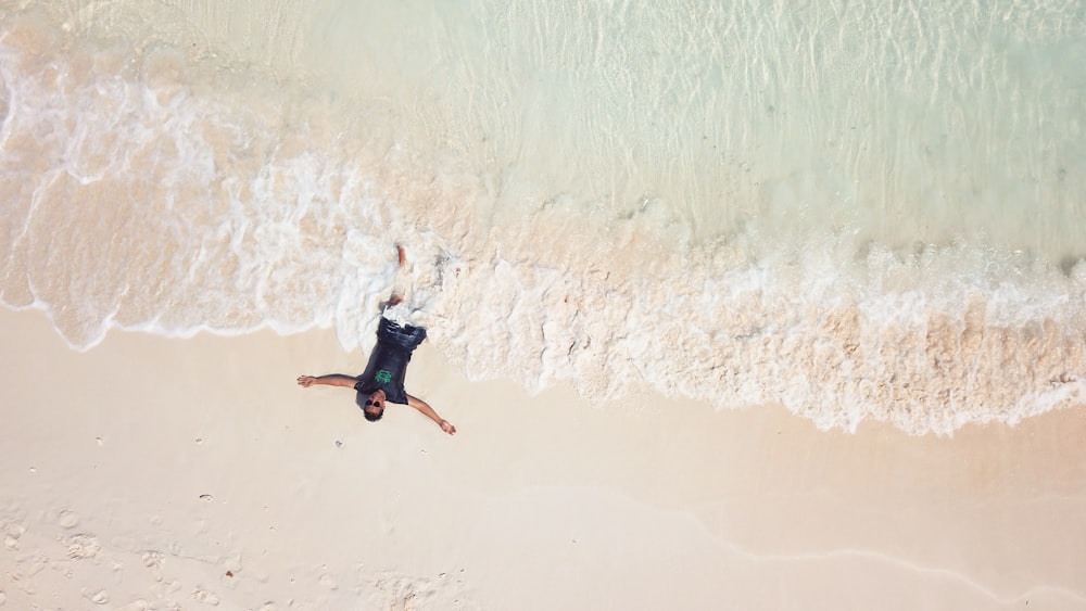 an aerial view of a man laying on the beach