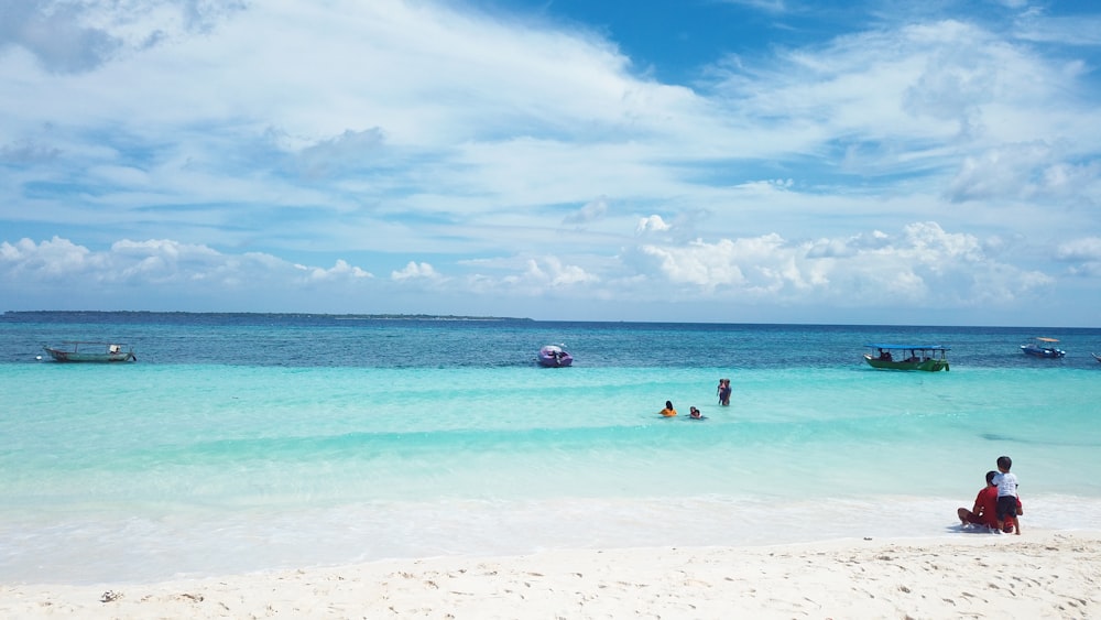 a group of people sitting on top of a sandy beach