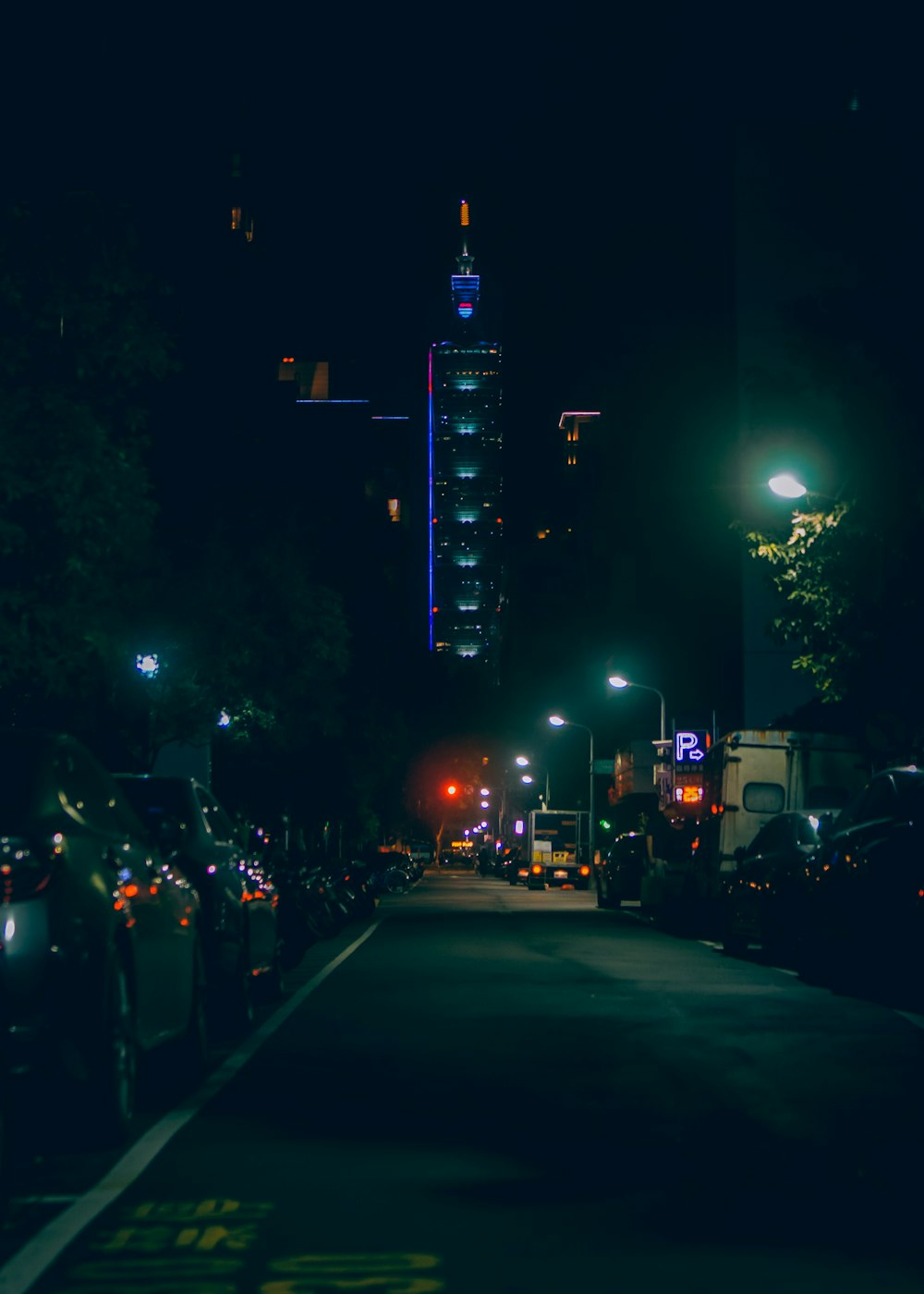 a city street at night with a tall building in the background