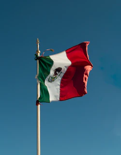 a mexican flag flying high in the sky