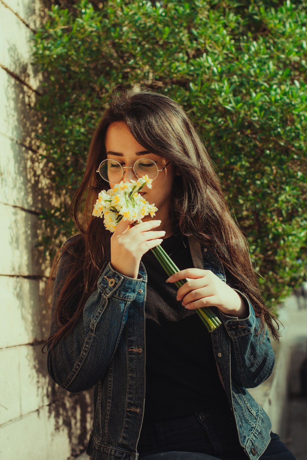 a woman with glasses is holding a flower