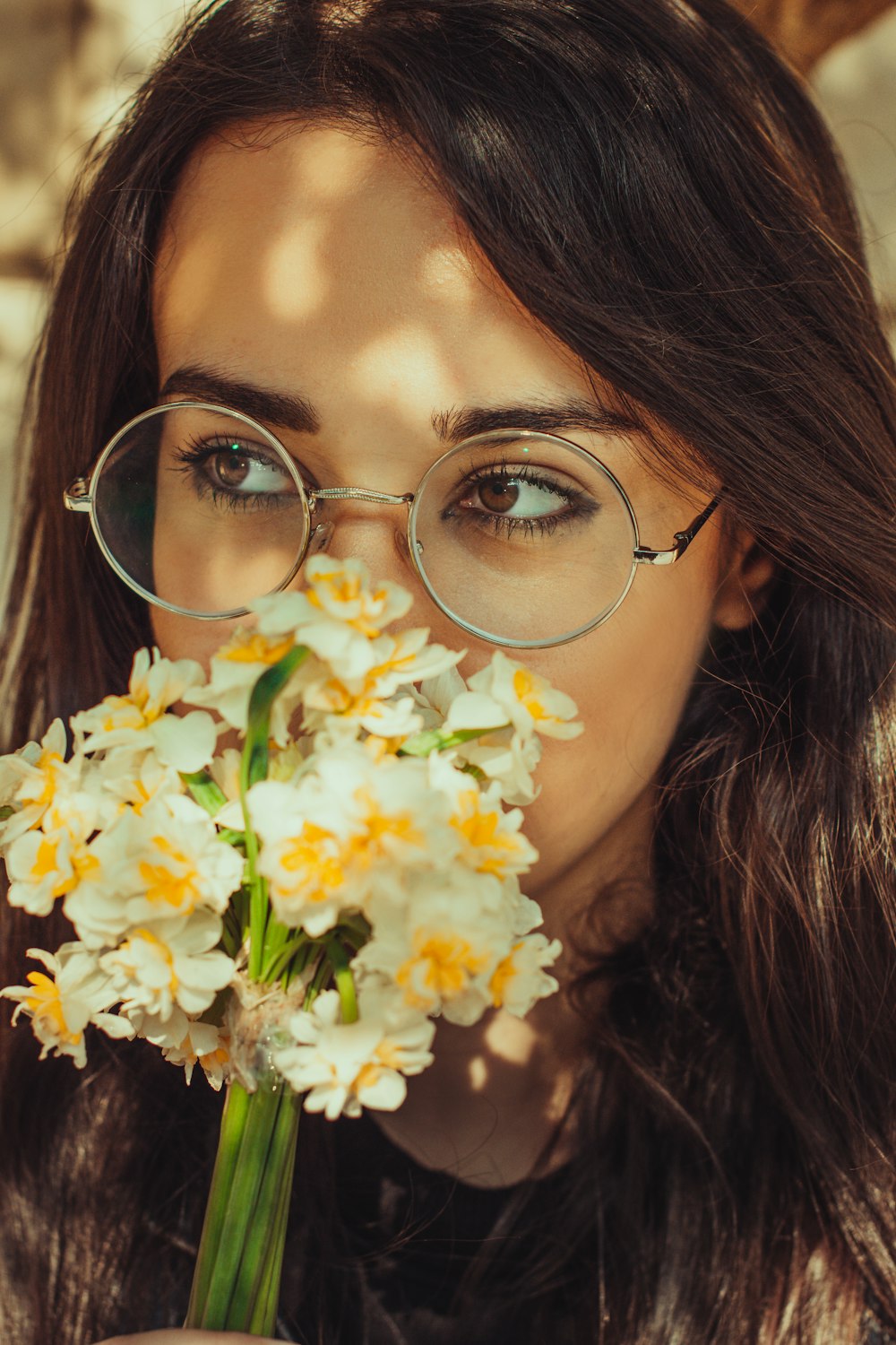 a woman with glasses holding a bunch of flowers