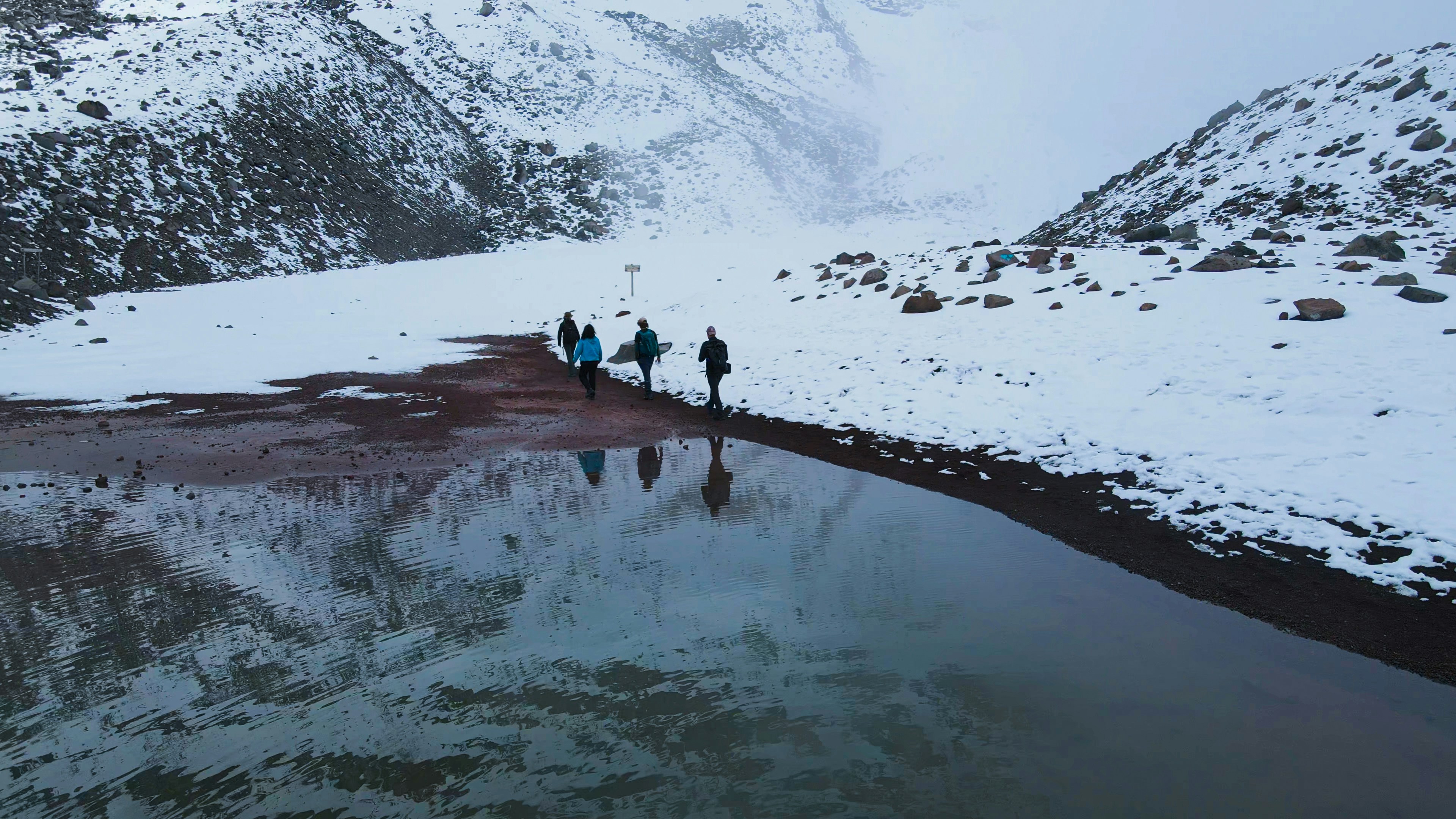 a group of people walking across a snow covered field, 