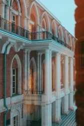 An elegant architectural structure featuring tall white columns, arched windows, and a brick exterior. The design exudes a sense of historical or classical style, with warm light visible through some windows, suggesting an inhabited space.