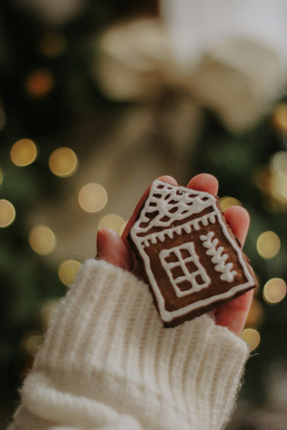 a person holding a cookie in front of a christmas tree