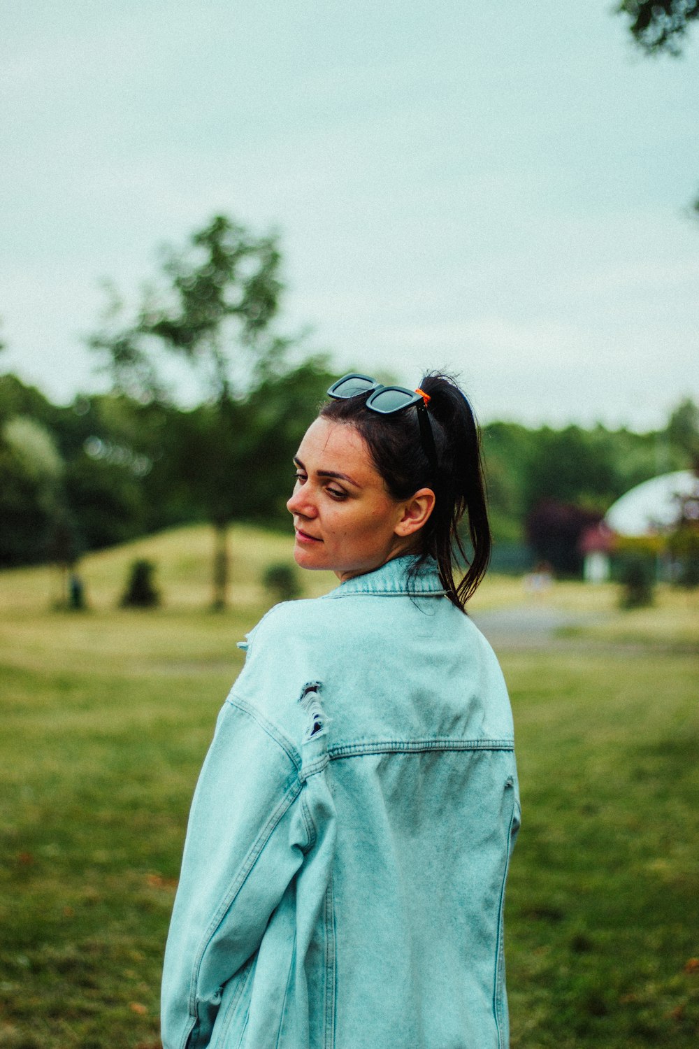 a woman in a blue jacket is standing in a field