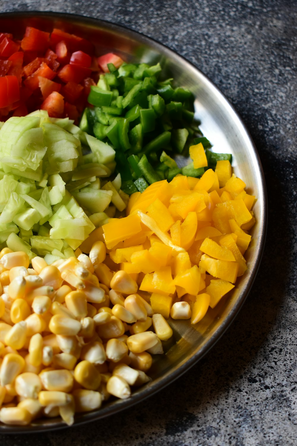 a metal bowl filled with chopped vegetables on top of a table