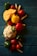 A variety of fresh vegetables including cauliflower, squash, bell peppers, cherry tomatoes, baby corn, and red tomatoes are arranged on a dark teal wooden surface.