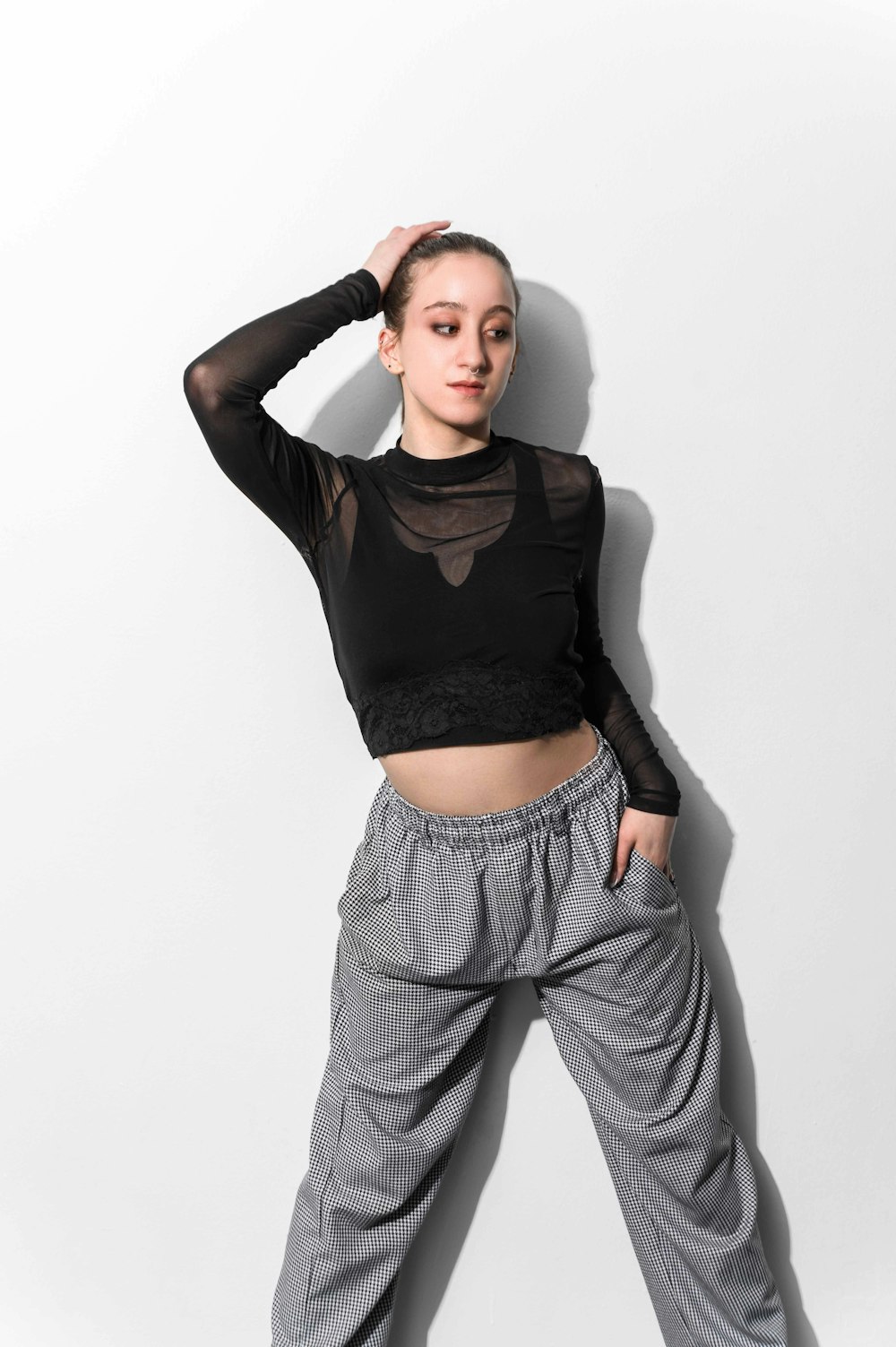 a woman posing in a black top and grey pants