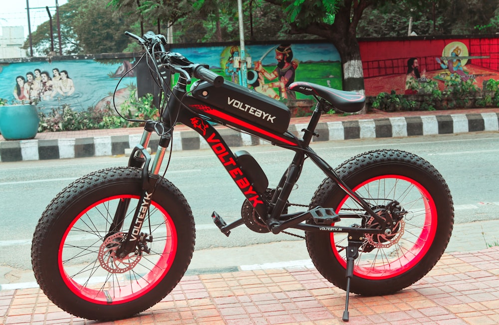 a black and red electric bike parked on the side of the road