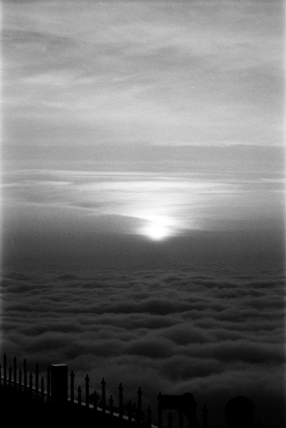 a black and white photo of the sun above the clouds