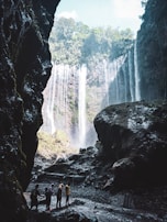 A group pausing to admire a hidden waterfall cascading into a crystal-clear pool in the jungle.