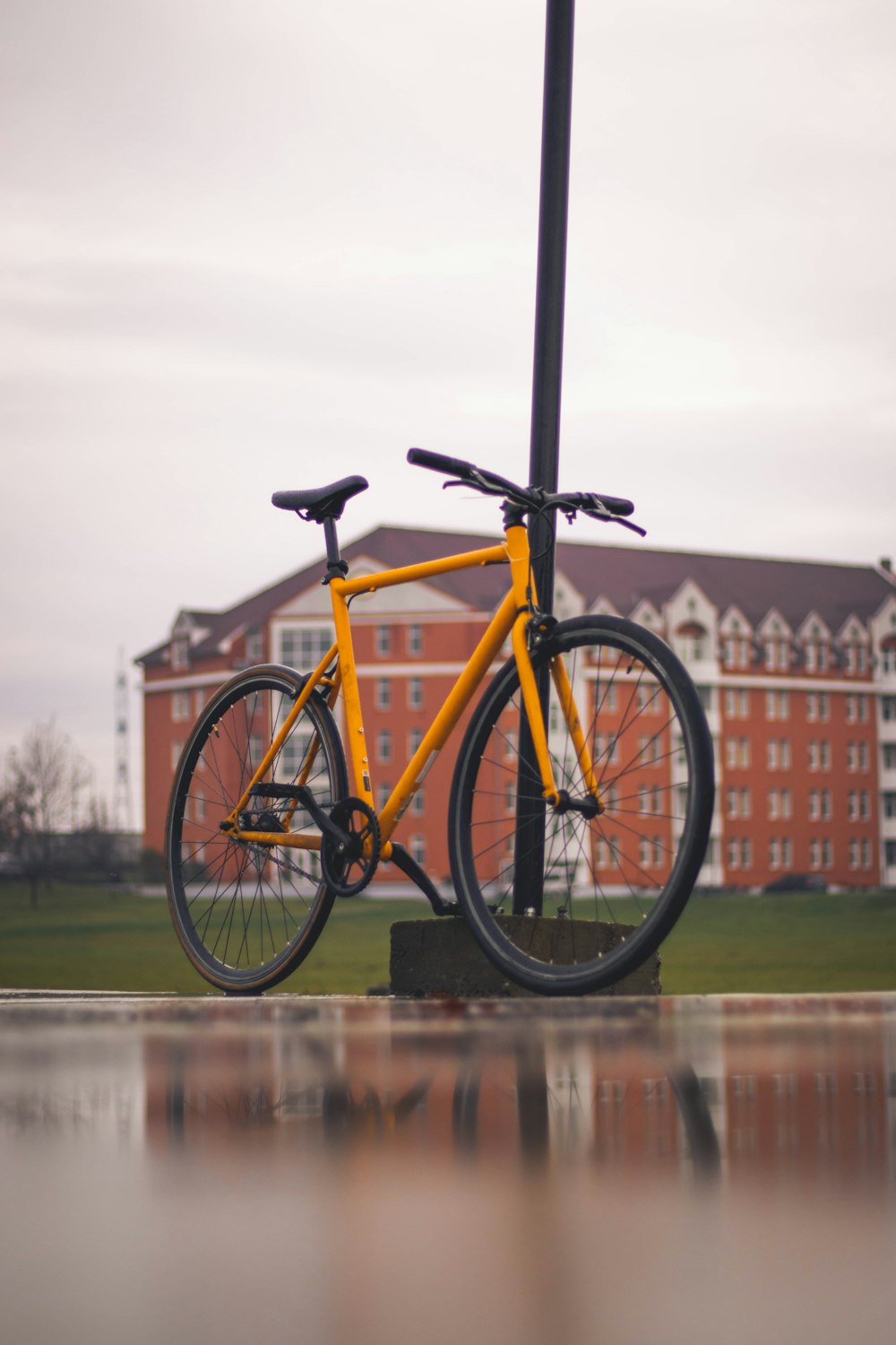a yellow bike is parked next to a pole