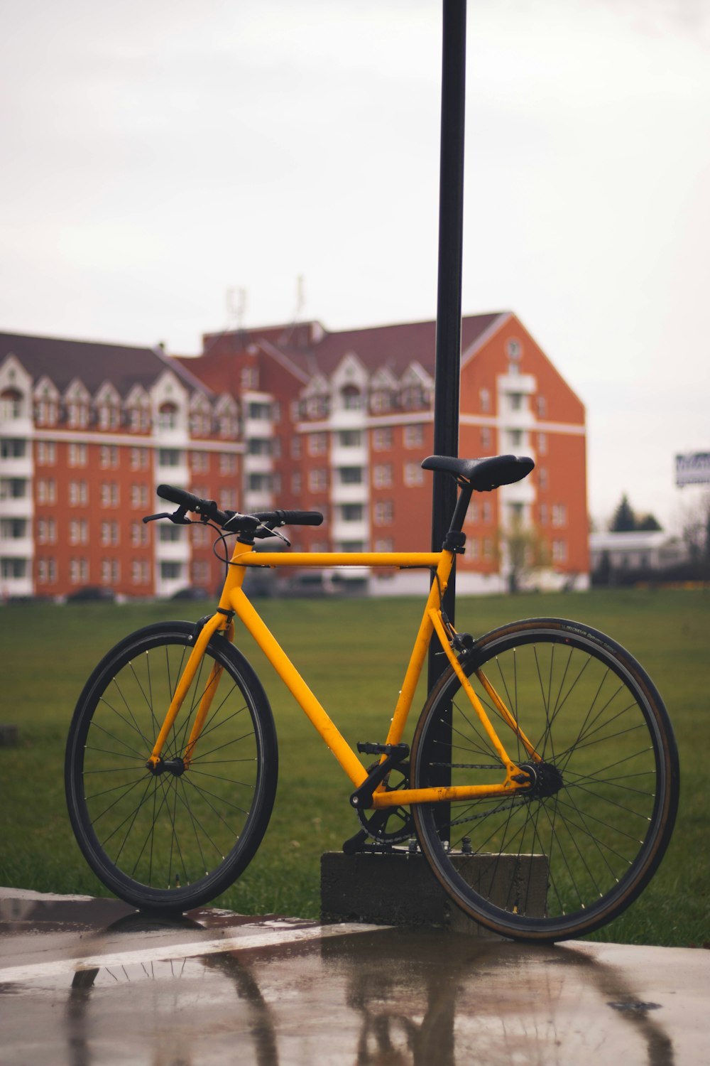 가로등 기둥 옆에 노란색 자전거가 주차되어 있습니다.
