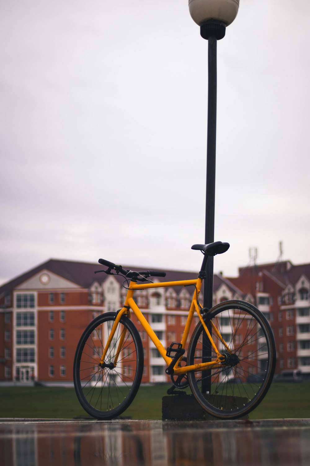 a yellow bicycle is chained to a lamp post