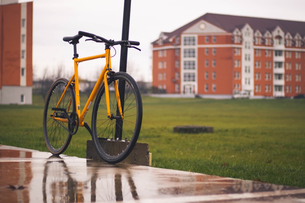 a yellow bike parked next to a pole in front of a building