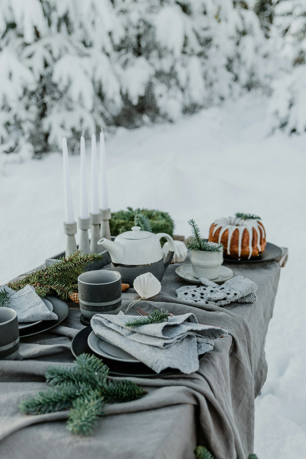 a table topped with dishes and candles in the snow