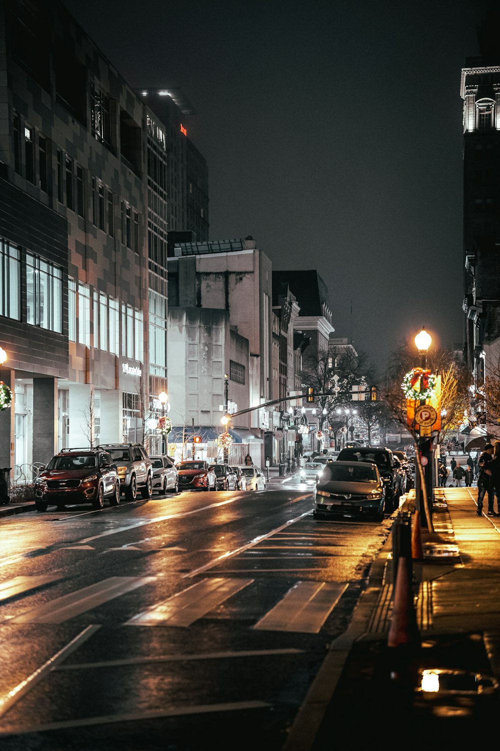 a city street at night with cars parked on the side of the road