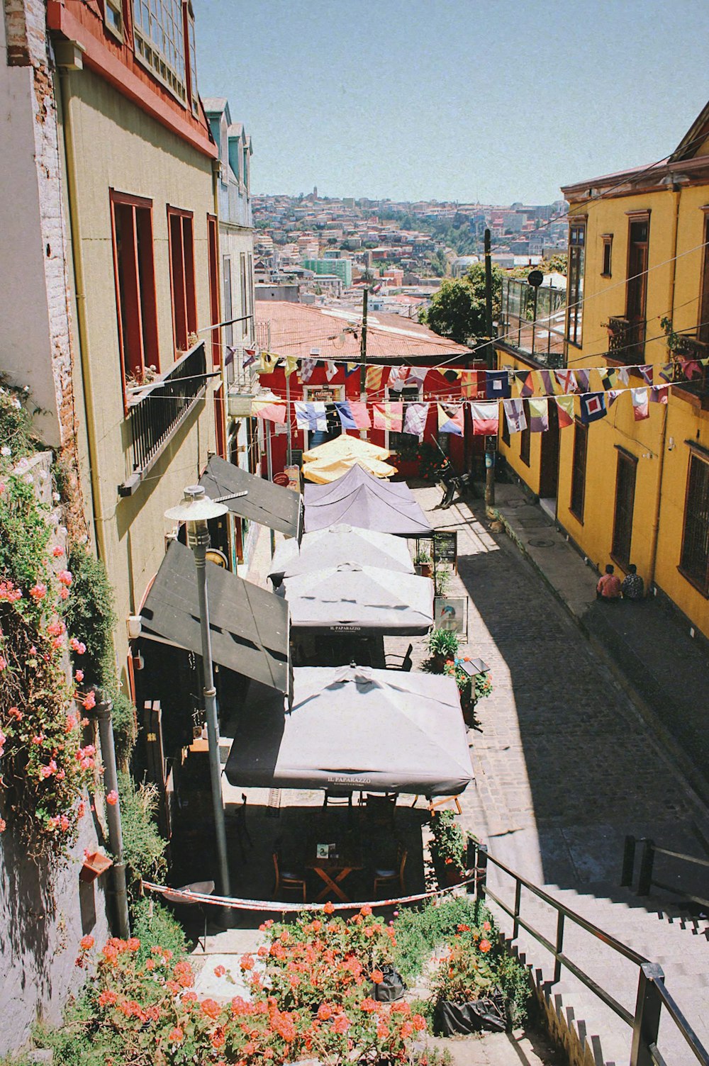 a narrow street with tables and umbrellas on the side