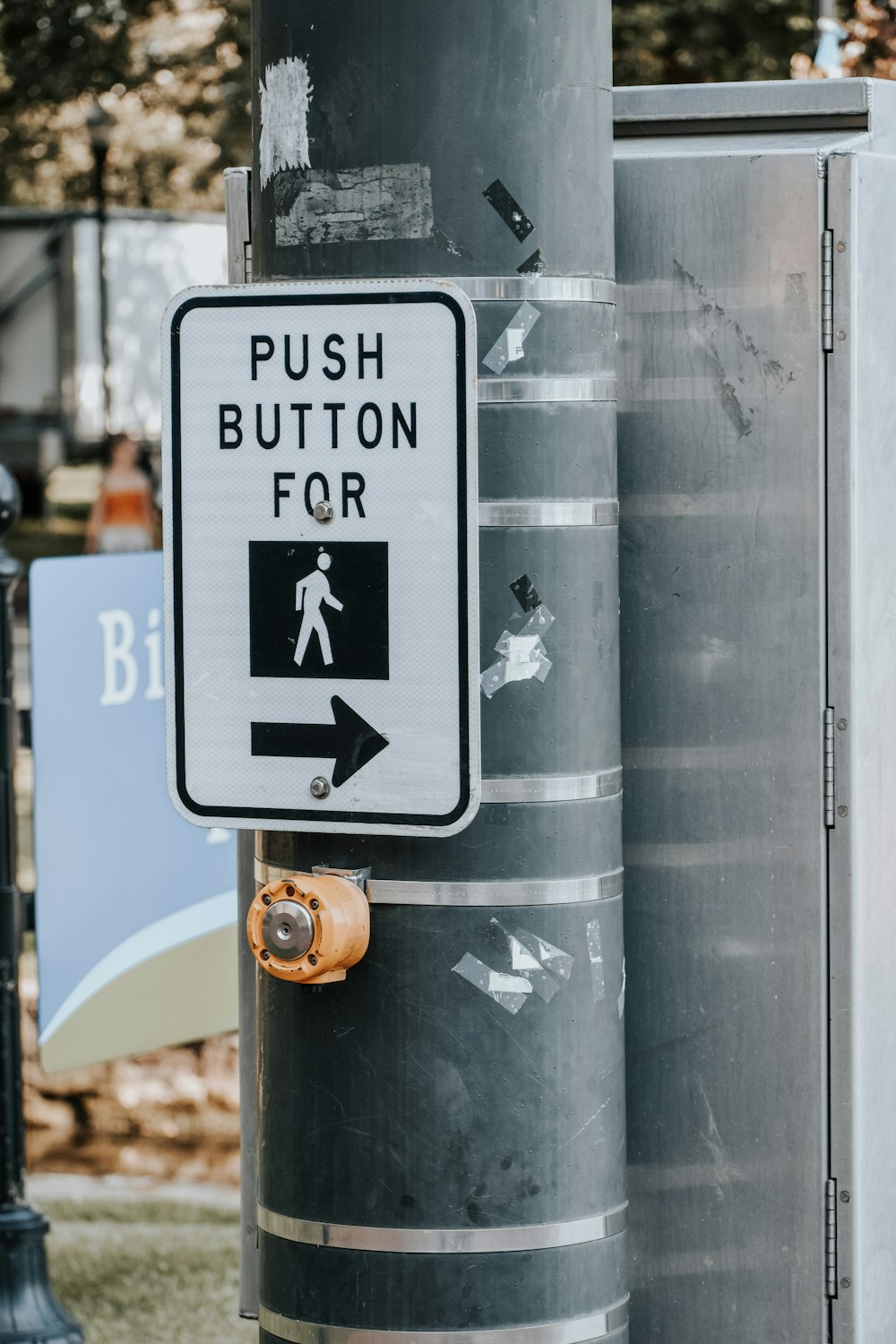 a sign on a pole that says push button for pedestrians