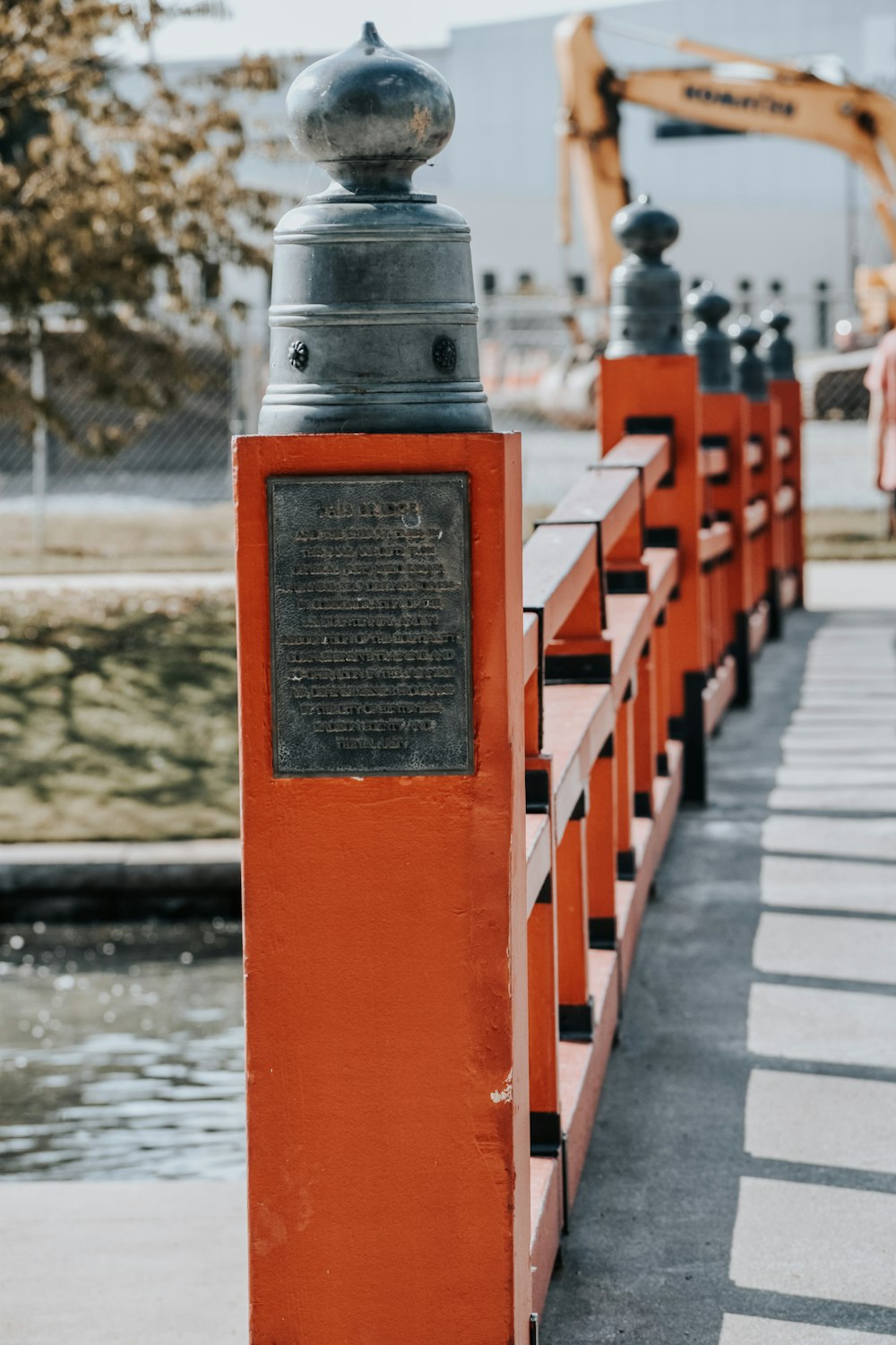 a row of orange railings with a statue on top of it