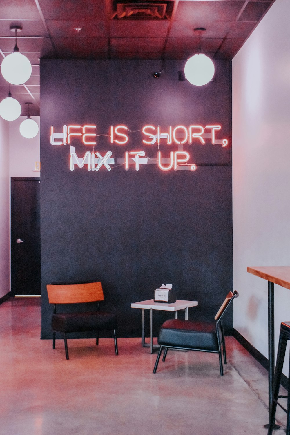 a room with a neon sign that says life is short, mix it up