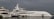 Several luxury yachts are docked at a marina under a cloudy sky. The water is calm, and the docks are lined with large, modern vessels, each with multiple decks and visible equipment such as antennas and lifeboats.