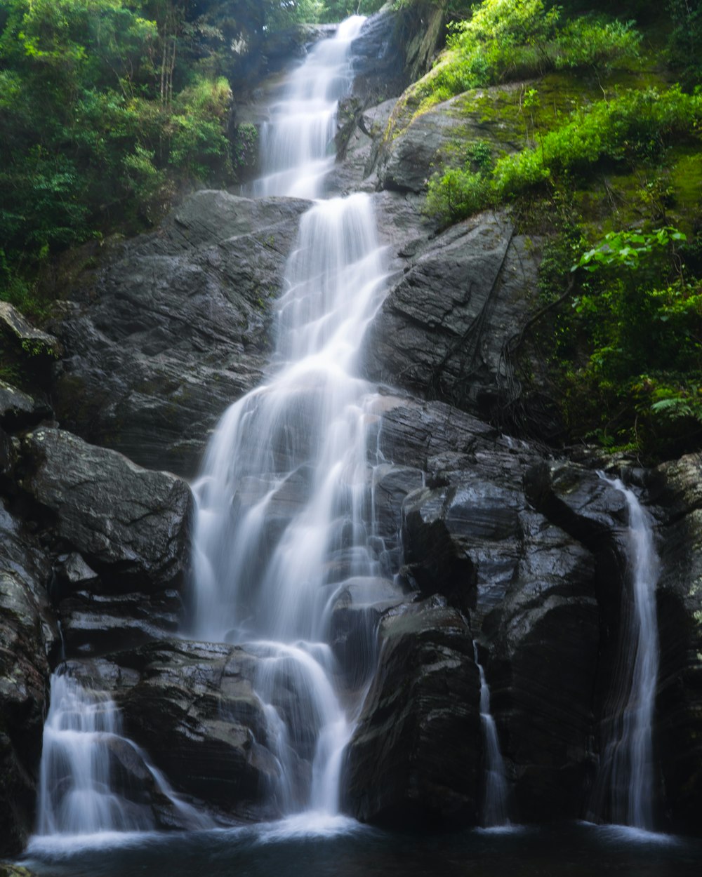 a small waterfall in the middle of a forest