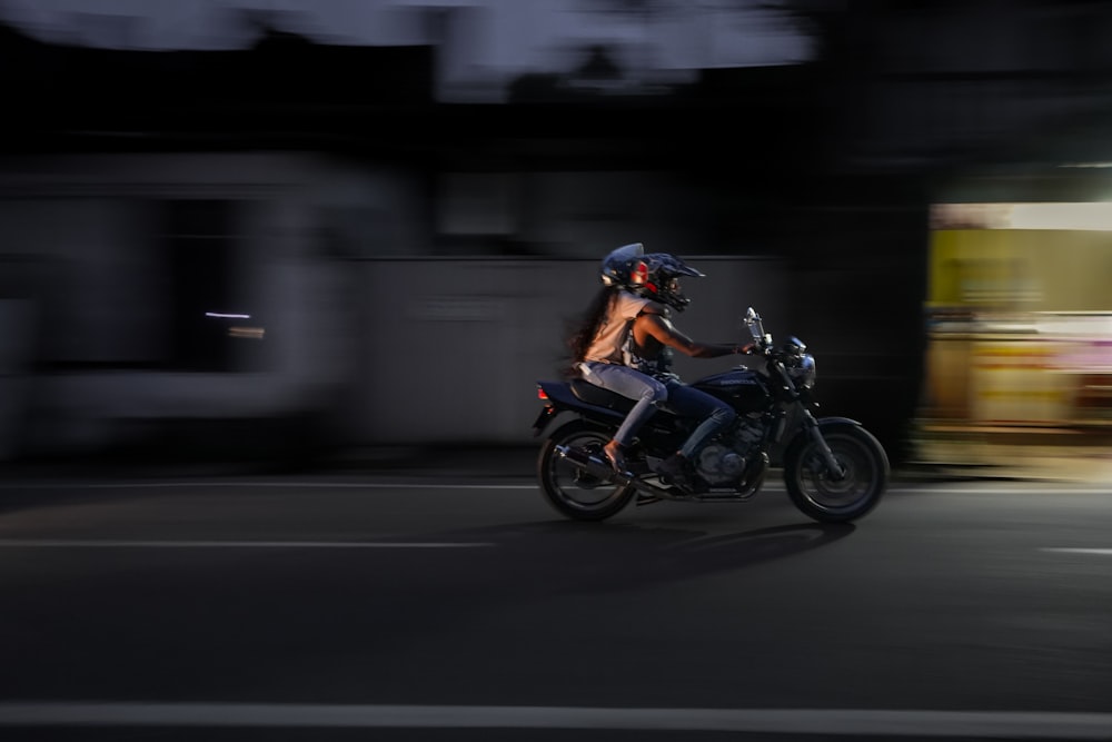 a man riding a motorcycle down a street at night