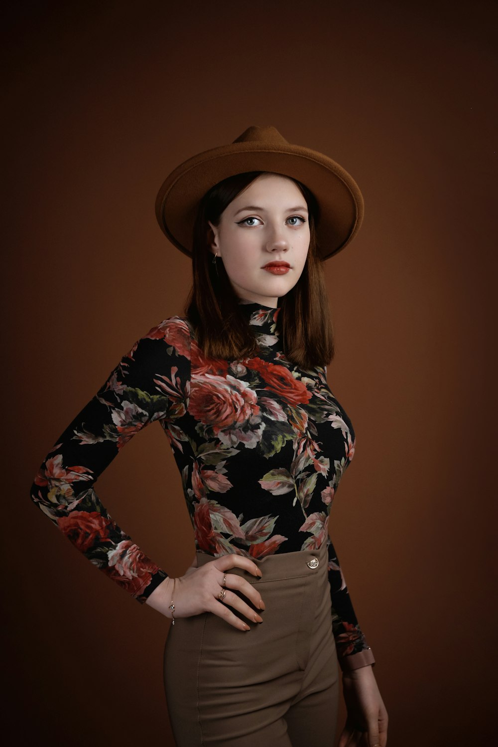a woman wearing a brown hat and a floral shirt