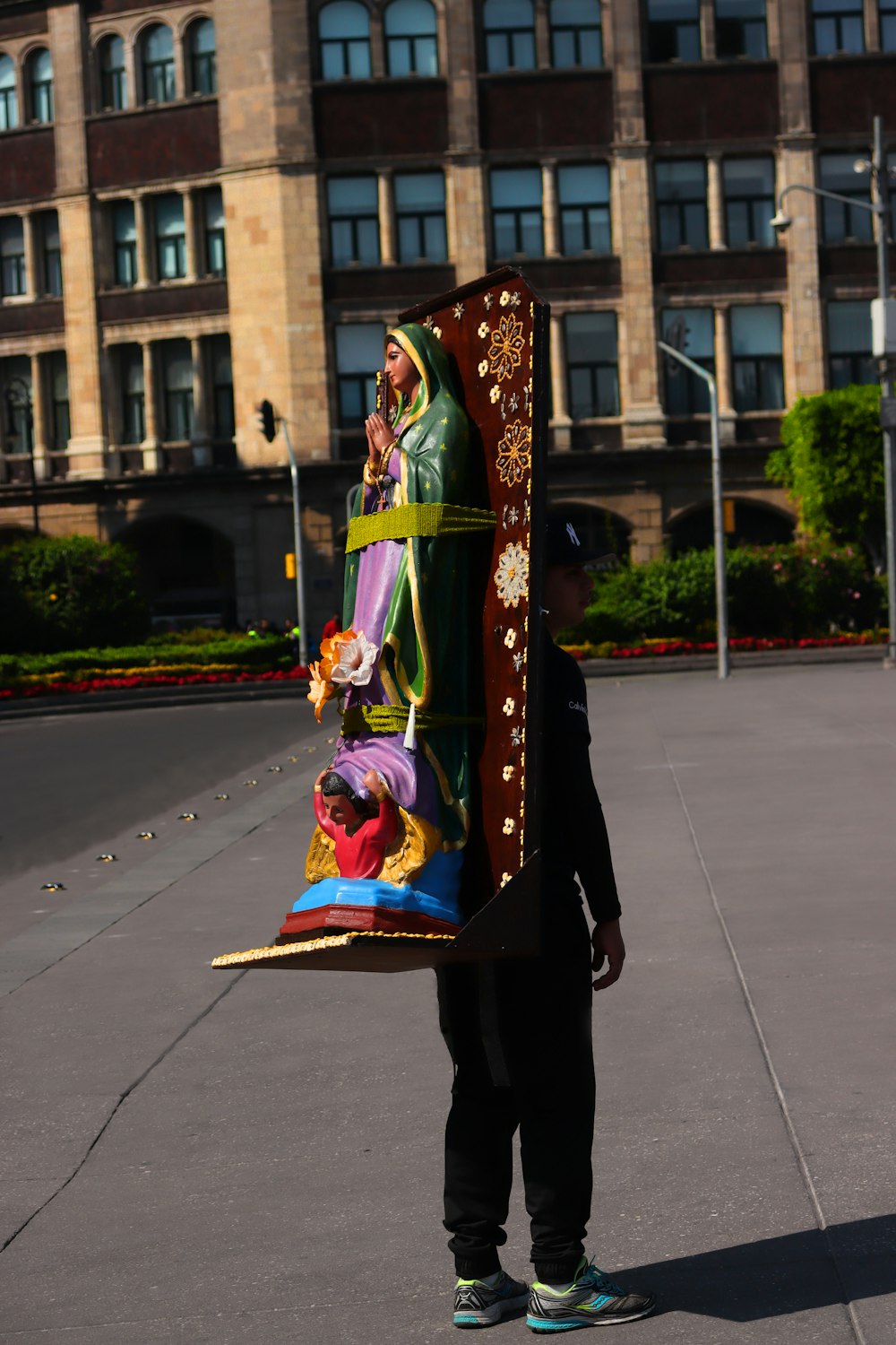 a person holding a large piece of art in front of a building