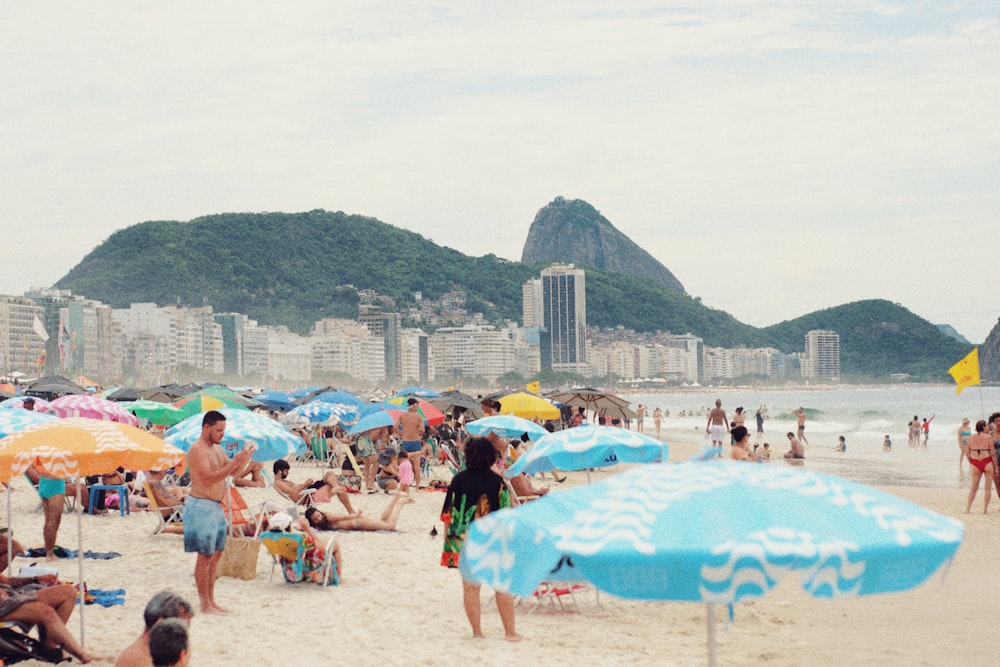 a crowded beach with many people and umbrellas