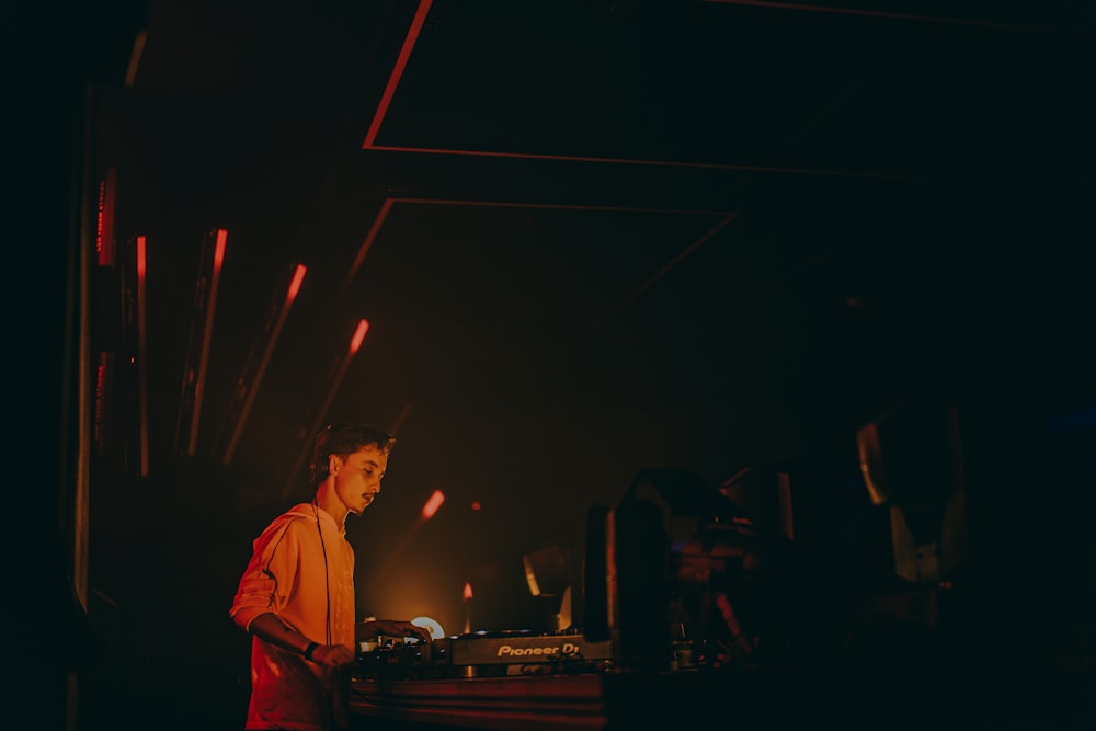 a man standing in front of a dj's turntable in a dark room