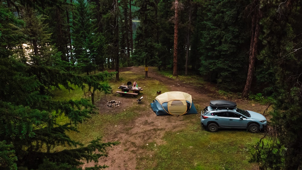 a car parked next to a tent in the woods