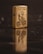 A metallic lighter with a detailed engraving of a cyclist and the word 'Cleveland' is placed upright on a dark reflective surface. The lighter's reflection is visible, creating a mirrored effect.