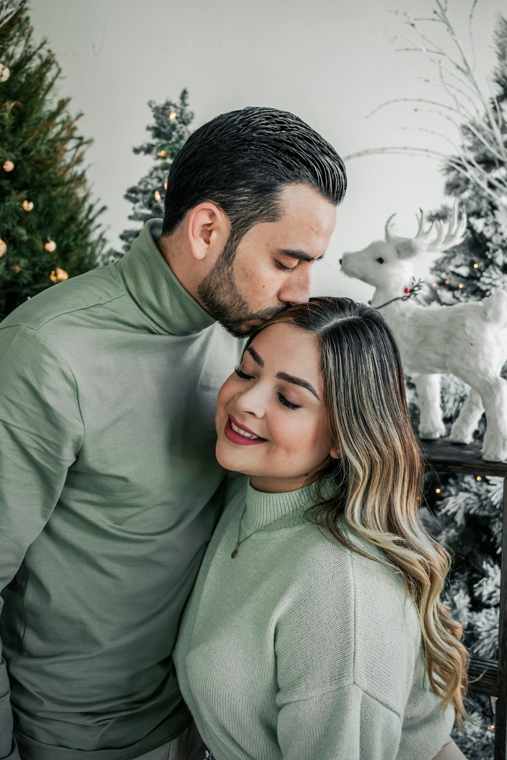 a man and a woman standing in front of a christmas tree