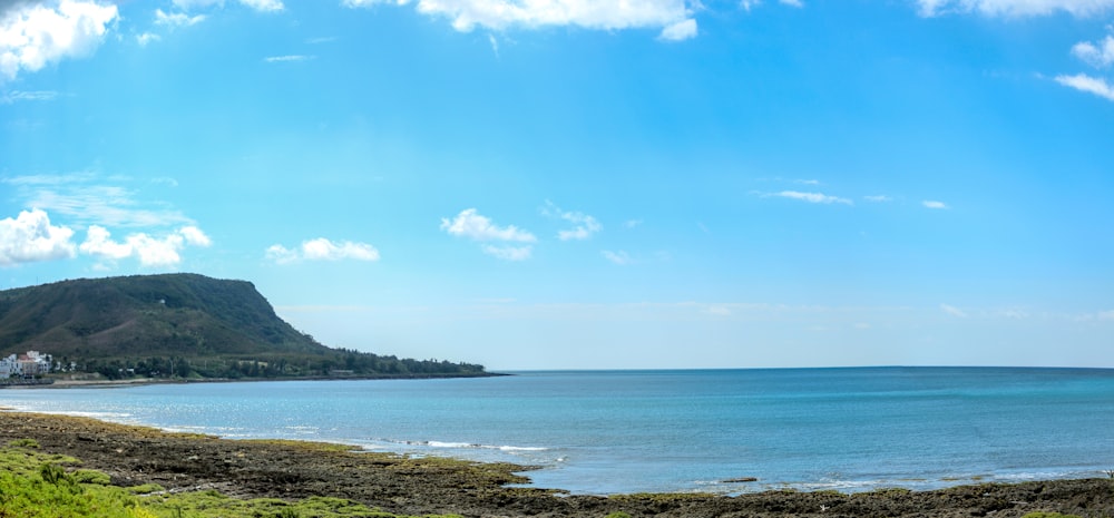 uma vista de uma praia com uma colina no fundo