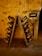 A rustic, dimly-lit wine cellar with an A-frame riddling rack holding numerous champagne bottles tilted downwards. The stone walls have a textured and aged appearance, with a small sign labeled 'SAVIGNY' mounted on the wall. The setting suggests an authentic and historic ambiance.