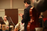 Close-up of a conductor leading an orchestra during a rehearsal.