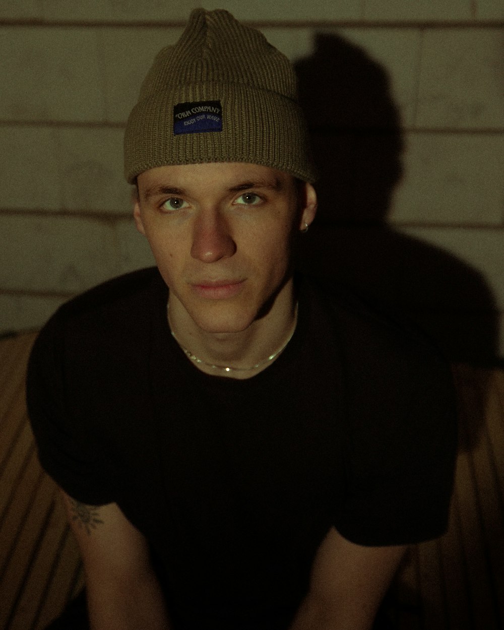 a young man wearing a beanie sitting on a bench