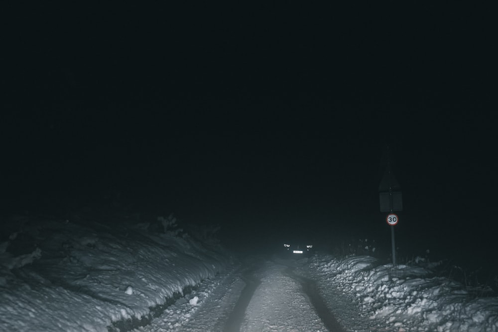 a car driving down a snow covered road at night