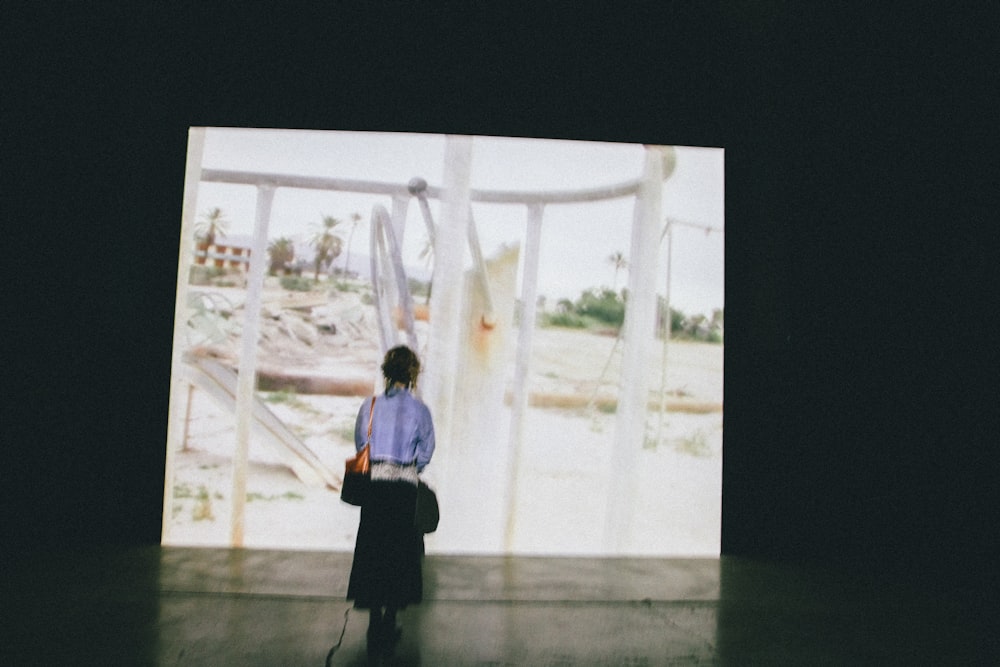 a woman standing in front of a large screen