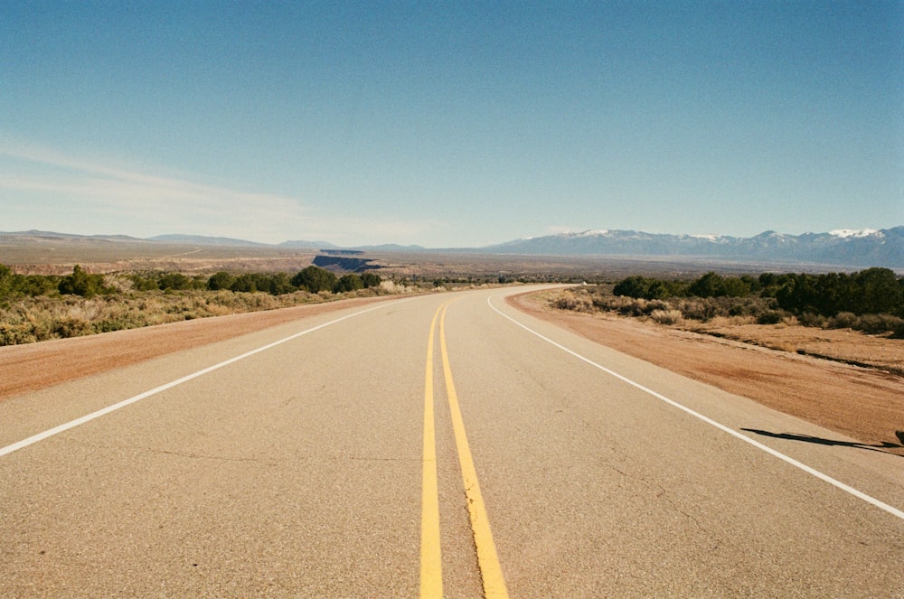 a long empty road with mountains in the distance