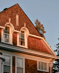 Cozy mountain home at sunset with beige and terracotta exterior walls surrounded by pine trees.