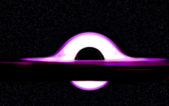 A luminous disc of bright, glowing light encircles a dark, circular void, representing a black hole in space. The light, varying in shades of magenta and pink, appears to bend around the singularity due to gravitational lensing. Surrounding the central form are countless specks of white, resembling distant stars in a vast galaxy.