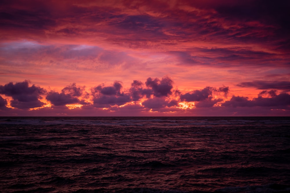 a beautiful sunset over the ocean with clouds