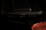 A close-up view of a smartphone's charging port area, including the USB-C port and speaker grills, with a dark background.