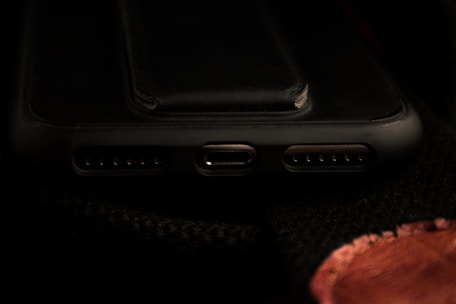 Close-up of a purple GaN charger plugged into a smartphone, glowing softly.